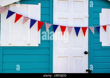 Union Jack Bunting sur une cabane colorée, pittoresque, turquoise et blanche de plage sur Westward Ho! Front de mer surplombant la plage et l'estuaire de Torridge. Banque D'Images