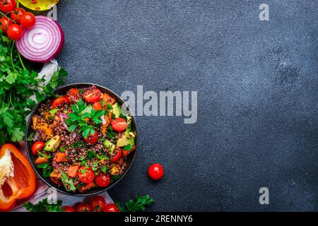 Salade de taboulé avec quinoa et tomates cerises, paprika rouge, avocat, concombres, oignon, persil. Plat moyen-oriental et arabe. Backgro de table noir Banque D'Images