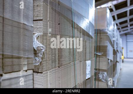 Boîtes pliantes en carton. Feuilles perforées de carton ondulé une pile sur palettes. Emballage de produits finis en production industrielle. Banque D'Images