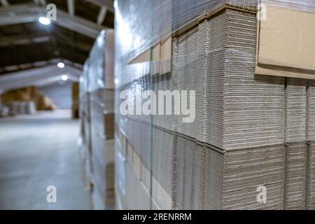 Boîtes pliantes en carton. Feuilles perforées de carton ondulé une pile sur palettes. Emballage de produits finis en production industrielle. Banque D'Images