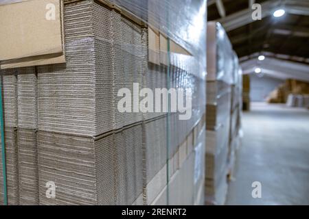 Boîtes pliantes en carton. Feuilles perforées de carton ondulé une pile sur palettes. Emballage de produits finis en production industrielle. Banque D'Images