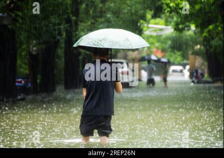 Chine. 29 juillet 2023. (230729) -- FUZHOU, 29 juillet 2023 (Xinhua) -- un homme traverse une zone inondée à Fuzhou, dans la province du Fujian, dans le sud-est de la Chine, le 29 juillet 2023. Les transports publics, y compris les bus et les métros à Fuzhou, ont été temporairement suspendus samedi matin après que la ville ait lancé une intervention d'urgence de niveau I pour les tempêtes de pluie déclenchées par le typhon Doksuri. Touchée par le typhon, Fuzhou a connu de fortes pluies continues depuis vendredi. Plusieurs stations d'observation météorologique de la ville ont enregistré les précipitations quotidiennes les plus élevées de l'histoire, conduisant à l'engorgement i Banque D'Images