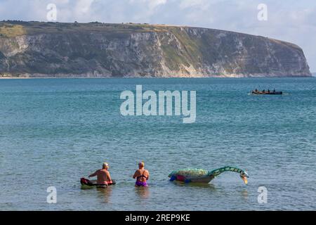 Swanage, Dorset, Royaume-Uni. 29 juillet 2023. Percy Seonster le dinosaure plésiosaure modèle fabriqué à partir de 600 bouteilles en plastique pesant 60-65kg créé par Glenn Martin sculptures est remorqué le long de la baie de Swanage par le nageur Oly Rush et d'autres nageurs. Une natation d'entraînement de 12 heures pour Oly, une partie de son programme d'entraînement intense pour sa tentative de record du monde, 24-30h de natation autour de la magnifique île d'Ithaca, Grèce en septembre. Visant à sensibiliser aux effets dévastateurs de la pollution plastique, ainsi que des fonds pour le projet planète Terre et mers saines. Crédit : Carolyn Jenkins/Alamy Live News Banque D'Images