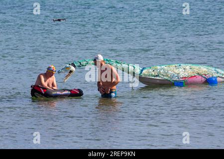 Swanage, Dorset, Royaume-Uni. 29 juillet 2023. Percy Seonster le dinosaure plésiosaure modèle fabriqué à partir de 600 bouteilles en plastique pesant 60-65kg créé par Glenn Martin sculptures est remorqué le long de la baie de Swanage par le nageur Oly Rush et d'autres nageurs. Une natation d'entraînement de 12 heures pour Oly, une partie de son programme d'entraînement intense pour sa tentative de record du monde, 24-30h de natation autour de la magnifique île d'Ithaca, Grèce en septembre. Visant à sensibiliser aux effets dévastateurs de la pollution plastique, ainsi que des fonds pour le projet planète Terre et mers saines. Crédit : Carolyn Jenkins/Alamy Live News Banque D'Images