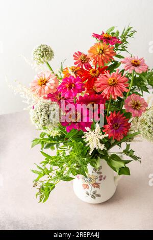 Bouquet d'été de Zinnia colorée, inflorescences d'oignon et brins de menthe, bouquet de fleurs sur la table près du mur, décoration de la maison avec des fleurs Banque D'Images