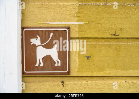 Panneau brun de stationnement de chien sur le mur d'un vieux bâtiment en bois jaune. Gros plan. Banque D'Images