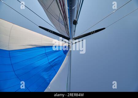 Voiles blanches et ciel bleu sous les tropiques. Yacht à voile en vacances dans l'océan. Mât, boom, drisse, voiles remplies de vent - jib, spinnaker, gênes, secteur Banque D'Images