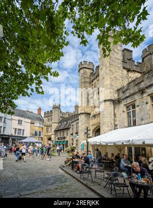 Cafés en plein air animés devant le porche sans sou et la porte du palais des Bishops le samedi du marché à Market place, Wells, Somerset, Royaume-Uni le 29 juillet 2023 Banque D'Images