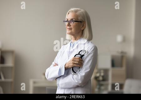 Pensive senior médecin femme en lunettes et manteau uniforme Banque D'Images