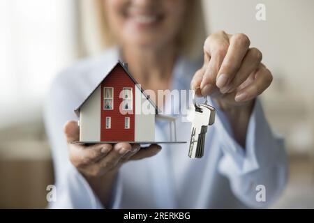 Agent immobilier mature tenant les clés et petit modèle de maison familiale Banque D'Images