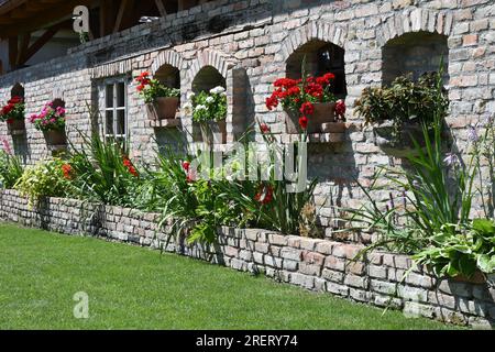 Mur de briques de jardin décoratif avec parterres de fleurs, coins muraux et pelouse verte en été Banque D'Images