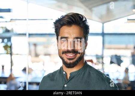 Souriant jeune homme d'affaires regardant la caméra dans le bureau, portrait de tête. Banque D'Images