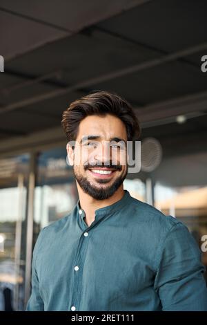 Heureux jeune homme d'affaires latin regardant la caméra, portrait vertical. Banque D'Images