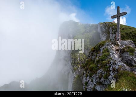 Brouillard dégageant la vue sur les falaises rocheuses escarpées et la croix sommitale sur le mont Schafberg dans la région autrichienne du Salzkammergut Banque D'Images