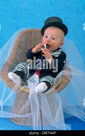 Bébé, 8 mois, petit homme en costume et chapeau haut avec mannequin à la main Banque D'Images