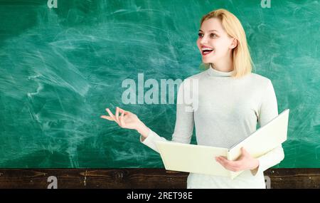 Enseignante souriante près du tableau dans la salle de classe de l'école. Enseignant donnant des leçons aux étudiants à l'école ou à l'université. Fille ou femme étudiante à l'université Banque D'Images