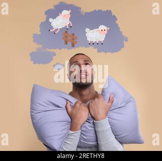 Insomnie. Homme fatigué essayant de s'endormir sur fond beige. Nuage de pensée avec illustration de moutons sautant par-dessus la clôture au-dessus de lui Banque D'Images