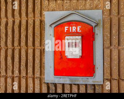 Boîte de tirage rouge d'alarme d'incendie vintage montée sur le côté d'un bâtiment municipal dans une ville. contexte. Gros plan. Banque D'Images