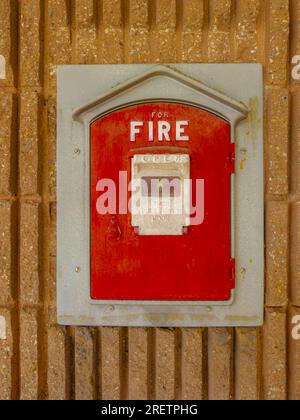 Boîte de tirage rouge d'alarme d'incendie vintage montée sur le côté d'un bâtiment municipal dans une ville. contexte. Gros plan. Banque D'Images