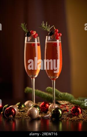 Verres avec champagne décoré de baies servis sur table avec des branches de conifères verts et boules de Noël colorées lors de l'événement festif Banque D'Images