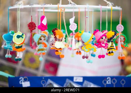 La foire artisanale vend des jouets tricotés colorés et de petites poupées. Banque D'Images