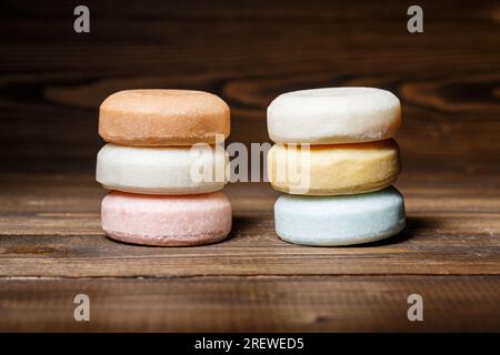 Barres colorées de shampooing sec rond sur un fond en bois. Cosmétique naturelle, soin de la peau et concept de dermatologie Banque D'Images