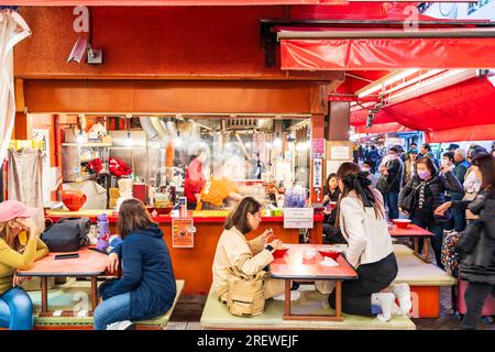 Le très populaire restaurant Kinryu Ramen à Dotonbori, Osaka. Les clients assis à de petites tables devant le comptoir mangent des nouilles le soir. Banque D'Images