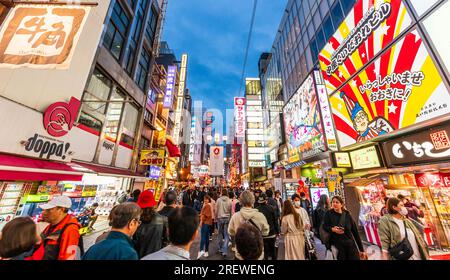 Des foules de touristes marchant dans la rue populaire Dotonbori à Osaka la nuit sous les lumières vives et les panneaux au néon pour les nombreux restaurants Banque D'Images