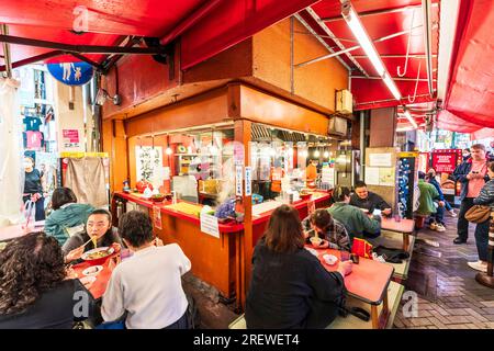 Le très populaire restaurant Kinryu Ramen à Dotonbori, Osaka. Les clients assis à de petites tables devant le comptoir mangent des nouilles le soir. Banque D'Images