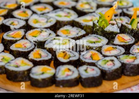 Un ensemble de rouleaux de sushi frais. Rouleaux de sushi disposés sur une plaque noire spéciale isolée sur fond gris. Sushi japonais savoureux. Sushi Rolls au saumon, av Banque D'Images