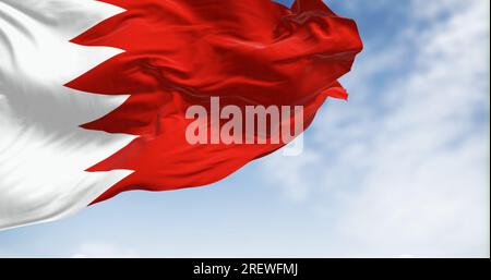 Drapeau national de Bahreïn brandissant par temps clair. Bande blanche à gauche et zone rouge à droite, séparées par cinq triangles formant un lin dentelé Banque D'Images