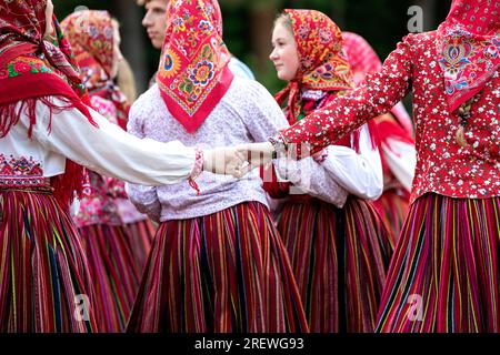 Filles en costumes folkloriques estoniens traditionnels se tenant la main, célébrant la fête nationale estonienne appelée Jaanipaev sur l'île de Kihnu, mer Baltique, Estonie Banque D'Images