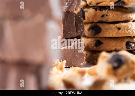 gros morceaux de chocolat au lait sur la table, chocolat cassé et biscuits de blé avec des gouttes de chocolat, aliments de restauration rapide, nourriture de cacao très calorique Banque D'Images