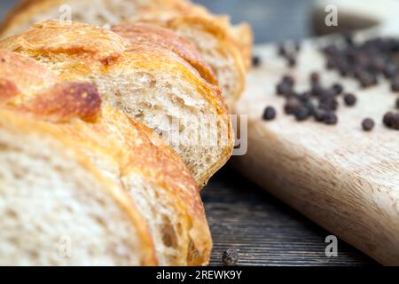 baguette en tranches avec des épices, nourriture à base de farine, à côté de grains de poivre noir séchés, qui est utilisé pour la cuisson, gros plan Banque D'Images