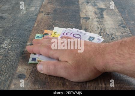 Euro cash. La main sur le montant des grands billets européens. L'argent sur le fond de table rustique en bois gros plan Banque D'Images