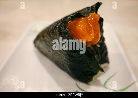 Juillet 2023, boule de riz japonaise (onigiri) avec jaune d'œuf cru mariné dans une sauce soja Banque D'Images