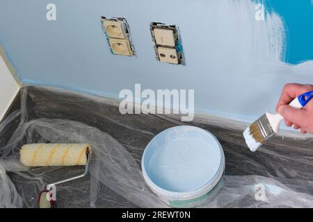 Peinture autour des prises électriques. retrait du cadre de la prise d'alimentation pour la peinture murale Banque D'Images