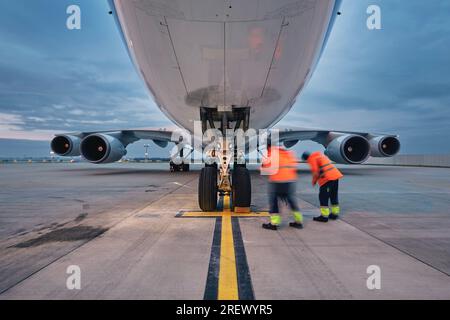 Vue à faible angle d'un avion de fret. Personnel au sol à l'aéroport. Préparation avion cargo avant le vol pendant la journée ensoleillée. Banque D'Images