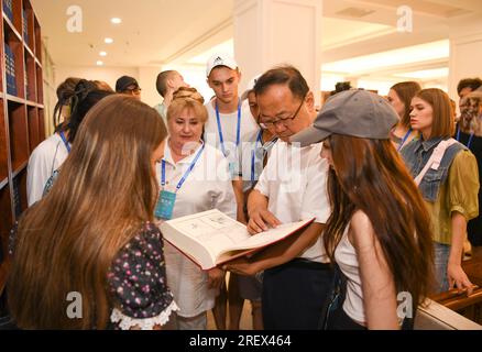 (230730) -- URUMQI, 30 juillet 2023 (Xinhua) -- un membre du personnel (2e R, avant) présente le canon de Yongle, la plus ancienne et la plus grande encyclopédie au monde compilée au début des années 1400, aux membres de troupes de danse étrangères visitant la bibliothèque du Xinjiang à Urumqi, dans la région autonome ouïgoure du Xinjiang, au nord-ouest de la Chine, le 23 juillet 2023. Sur le thème « rêves de danse, harmonie de la route de la soie », le 6e Festival international de danse du Xinjiang de Chine a attiré plus de 1 000 artistes de pays et régions d'Asie, d'Europe et d'Afrique, et ils devraient présenter quelque 60 spectacles bien connus. (Xinhua/Hu Huhu) Banque D'Images