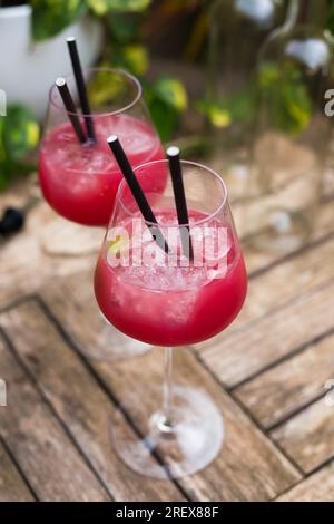 Cocktail rouge avec de la glace en verre avec tige sur surface en bois Banque D'Images