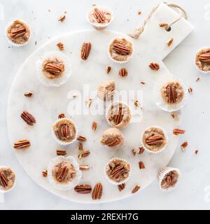 Tartelettes de noix de pécan au caramel salé éparpillées sur une planche de marbre blanc. Banque D'Images