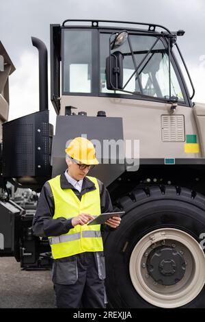 Ingénieur avec tablette se tient à côté du camion minier. Banque D'Images