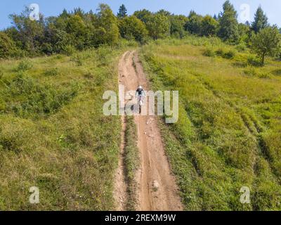 Athlète enduro sur le chemin forestier par une journée ensoleillée d'été. Vue aérienne du drone Banque D'Images