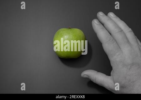 Nourriture saine. Le concept de consommation alimentaire saine. La main d'un homme en bw atteint une pomme verte mûre. Banque D'Images