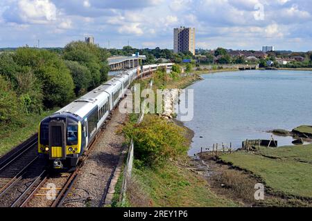 Un train électrique de 10 voitures de London Waterloo à Weymouth traverse Redbridge Causeway. Le River Test entre dans Southampton Water ici. Banque D'Images