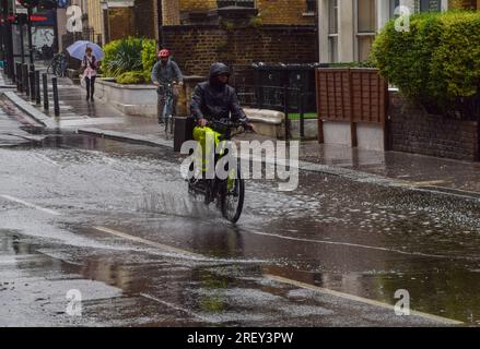 Londres, Angleterre, Royaume-Uni. 30 juillet 2023. Un cycliste traverse une grande flaque d'eau dans le centre de Londres tandis qu'une douche de pluie arrose la capitale. (Image de crédit : © Vuk Valcic/ZUMA Press Wire) USAGE ÉDITORIAL SEULEMENT! Non destiné à UN USAGE commercial ! Banque D'Images