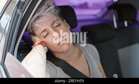 Jeune femme passager assis sur la voiture dormant dans la rue Banque D'Images