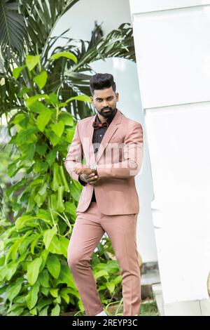 Bel homme indien en costume rose posant dans le jardin Banque D'Images