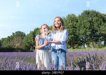 Deux amies adolescentes sur la lavande fleurie. Rire, profiter des vacances d'été Banque D'Images