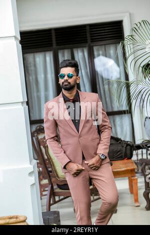 Beau jeune homme indien en costume beige et lunettes de soleil Banque D'Images